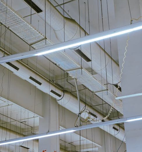 High-angle view of industrial ceiling showing exposed ducts and modern lighting.