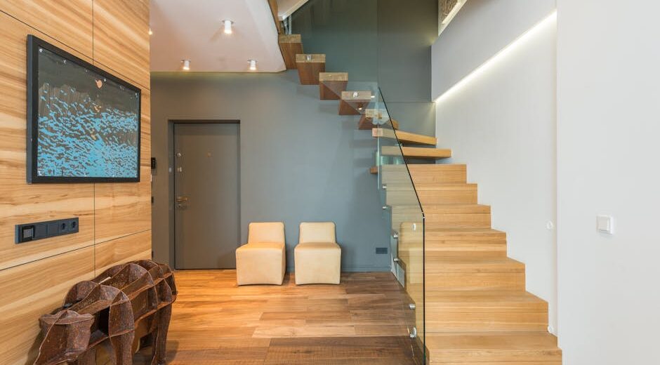 Contemporary stylish house hallway interior with creative statue under TV set cozy chairs and wooden stairway