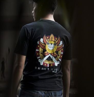 Man wearing black t-shirt with colorful graphic design and jeans in a natural setting.